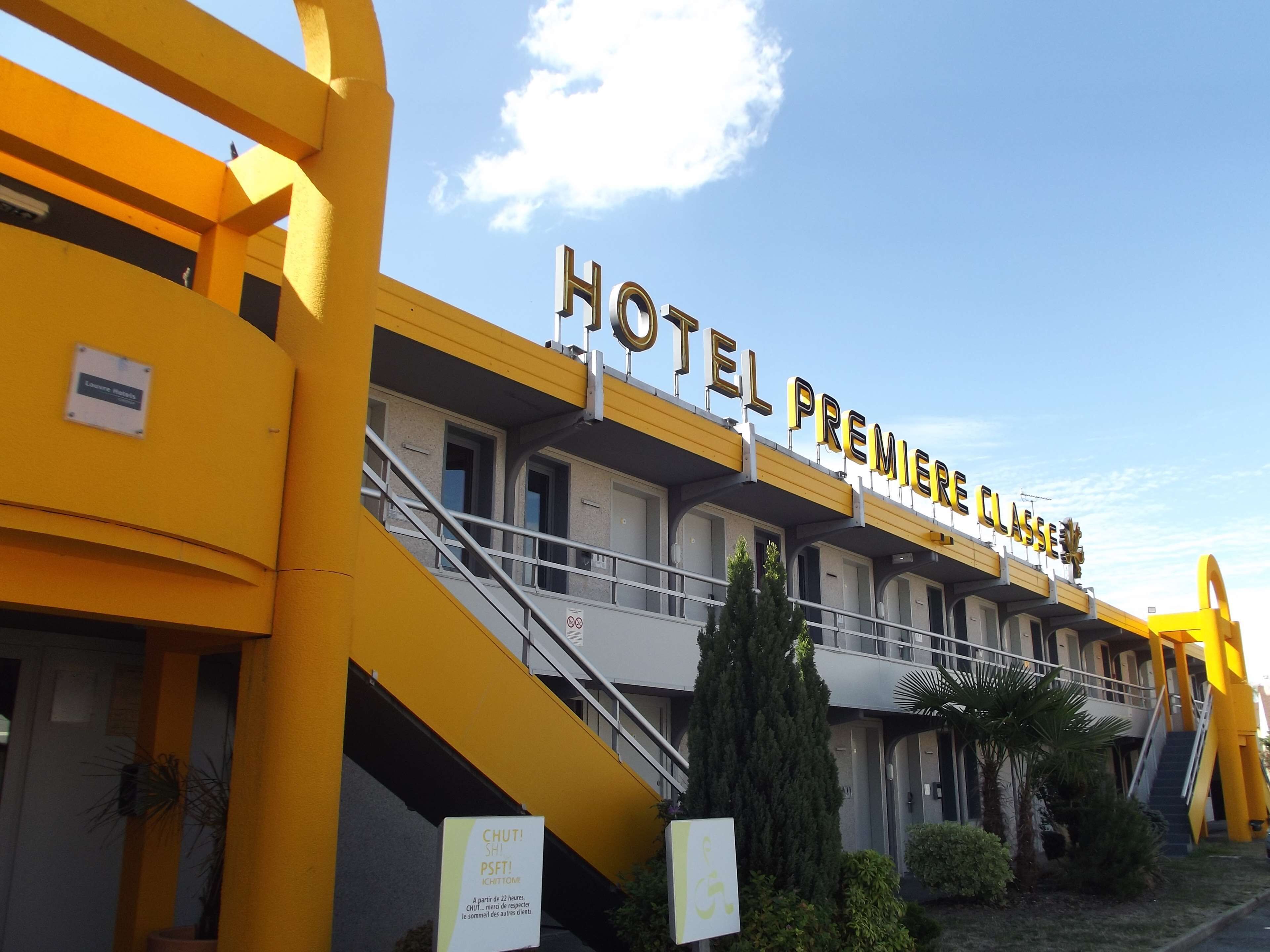 Un hôtel appelé « HOTEL PREMIERE CLASSE », avec une façade jaune, de nombreux balcons et un escalier menant à l’entrée.