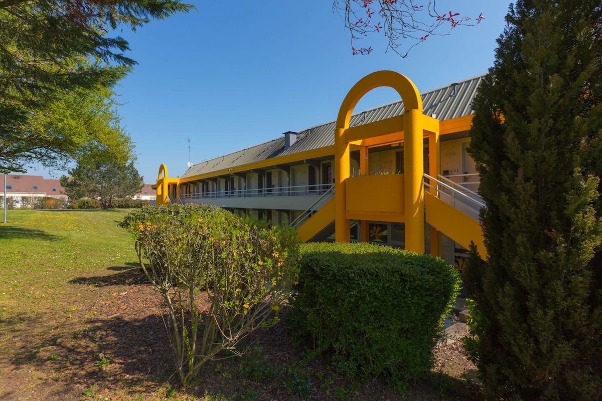 A yellow building with a modern design, featuring a staircase and a covered outdoor area.