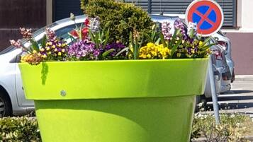 A green planter with flowers and a no parking sign.