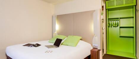 Een hotelkamer met een bed, een laptop en een groene kast.