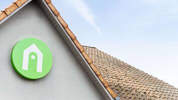 Un edificio con un logotipo verde en la fachada, techo de tejas y pared gris.