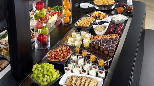 Una mesa de buffet con diferentes opciones de comida, incluyendo frutas, pastelería y postres.