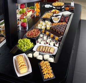 Una mesa de buffet con diferentes opciones de comida, incluyendo frutas, pastelería y postres.