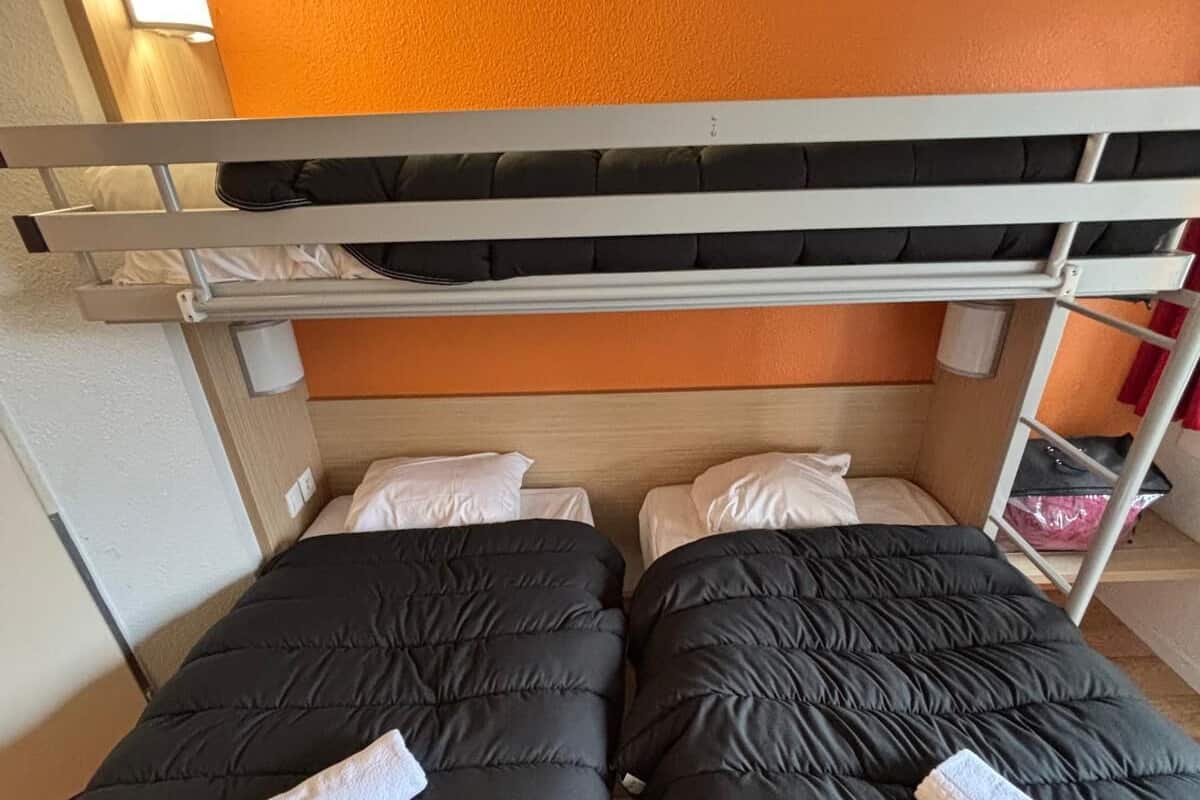 A bunk bed room with two beds, each with a black quilted mattress and a pillow.