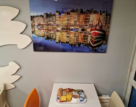 A breakfast tray with croissants, yogurt, juice, and coffee on a white table.