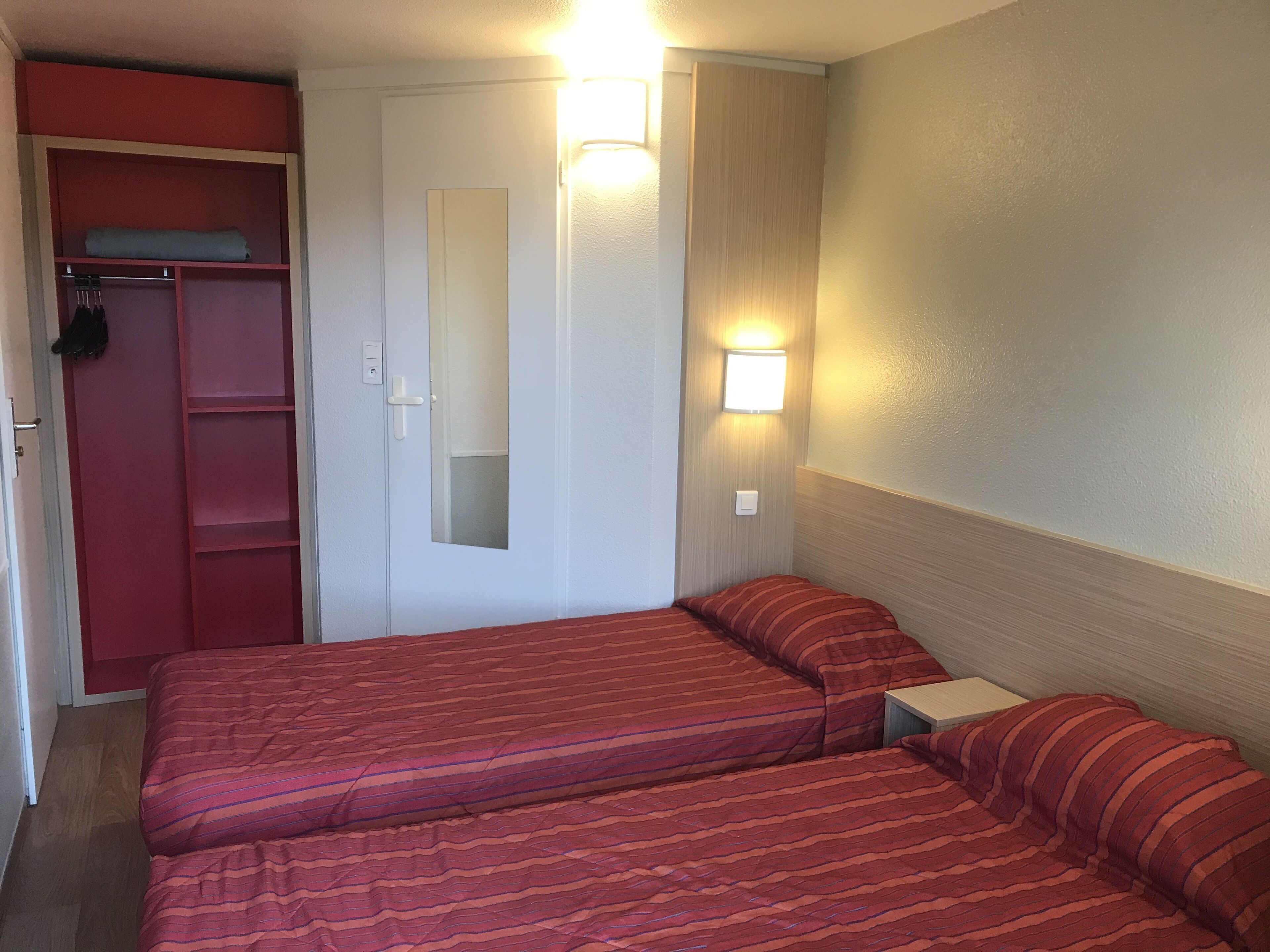 Habitación de hotel con dos camas, un armario y un espejo.