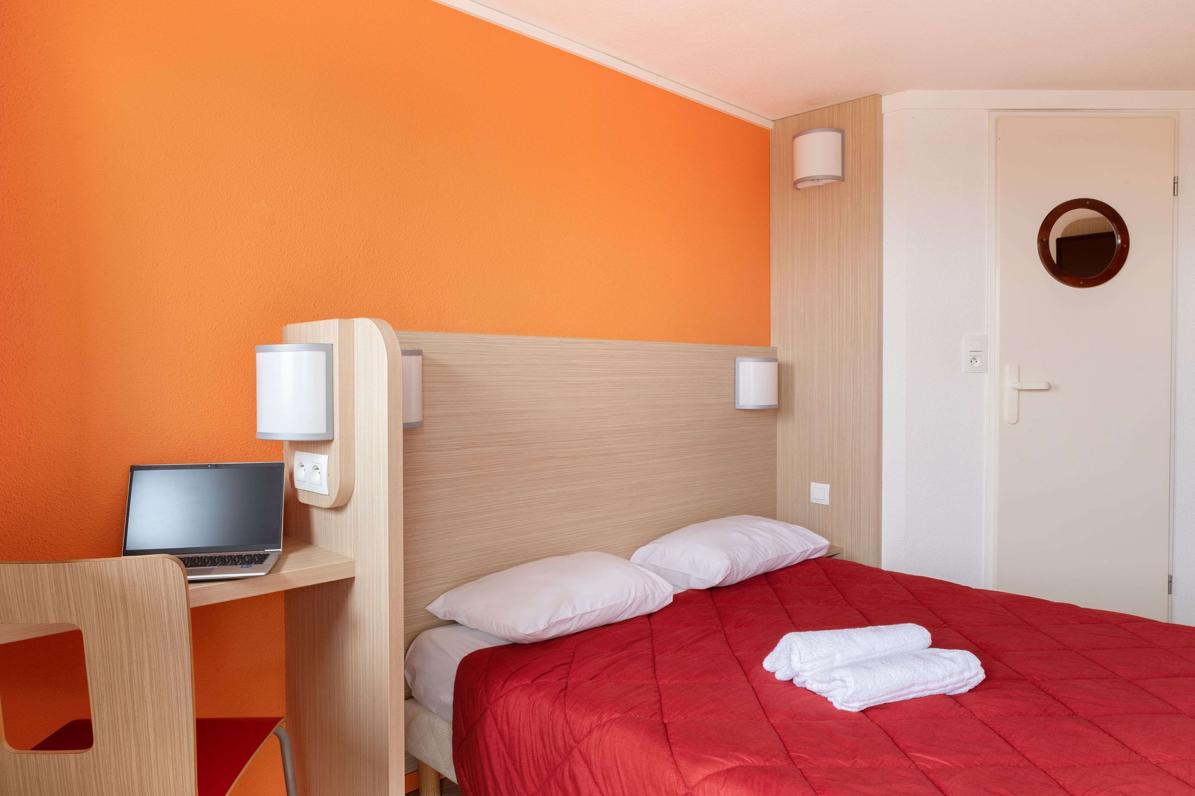Une chambre d’hôtel avec un lit, un bureau avec un ordinateur portable et une chaise.