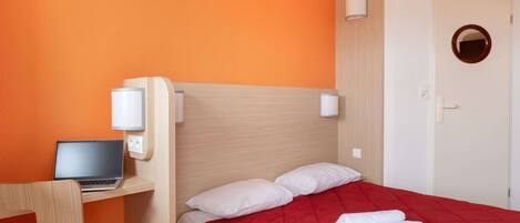 Une chambre d’hôtel avec un lit, un bureau avec un ordinateur portable et une chaise.