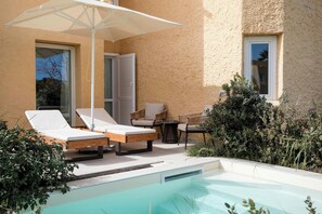 Relax by the pool surrounded by lush greenery and comfortable lounge chairs.