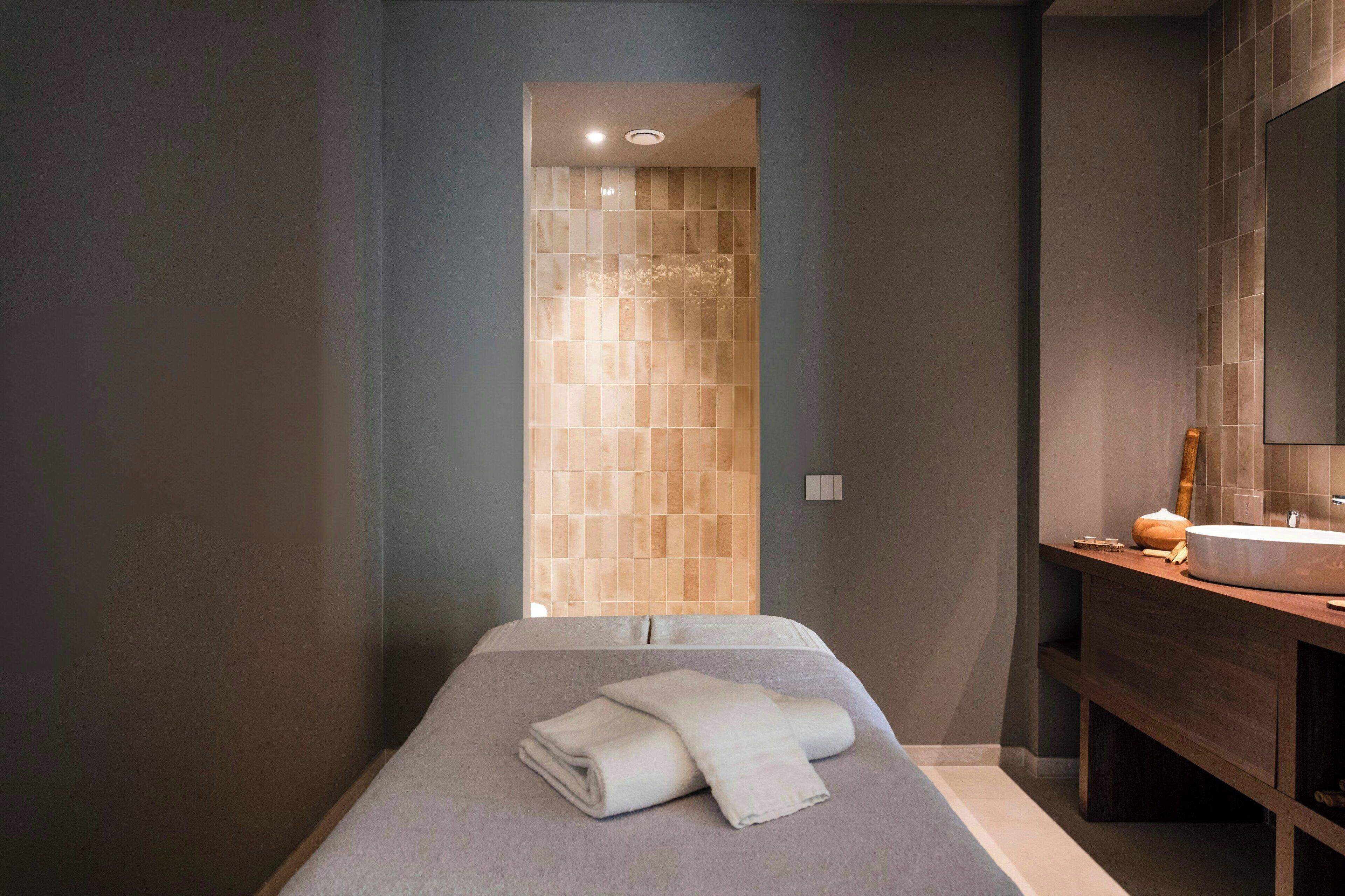 Un baño moderno con un espejo grande, un mueble de tocador de madera y una toalla en el suelo.