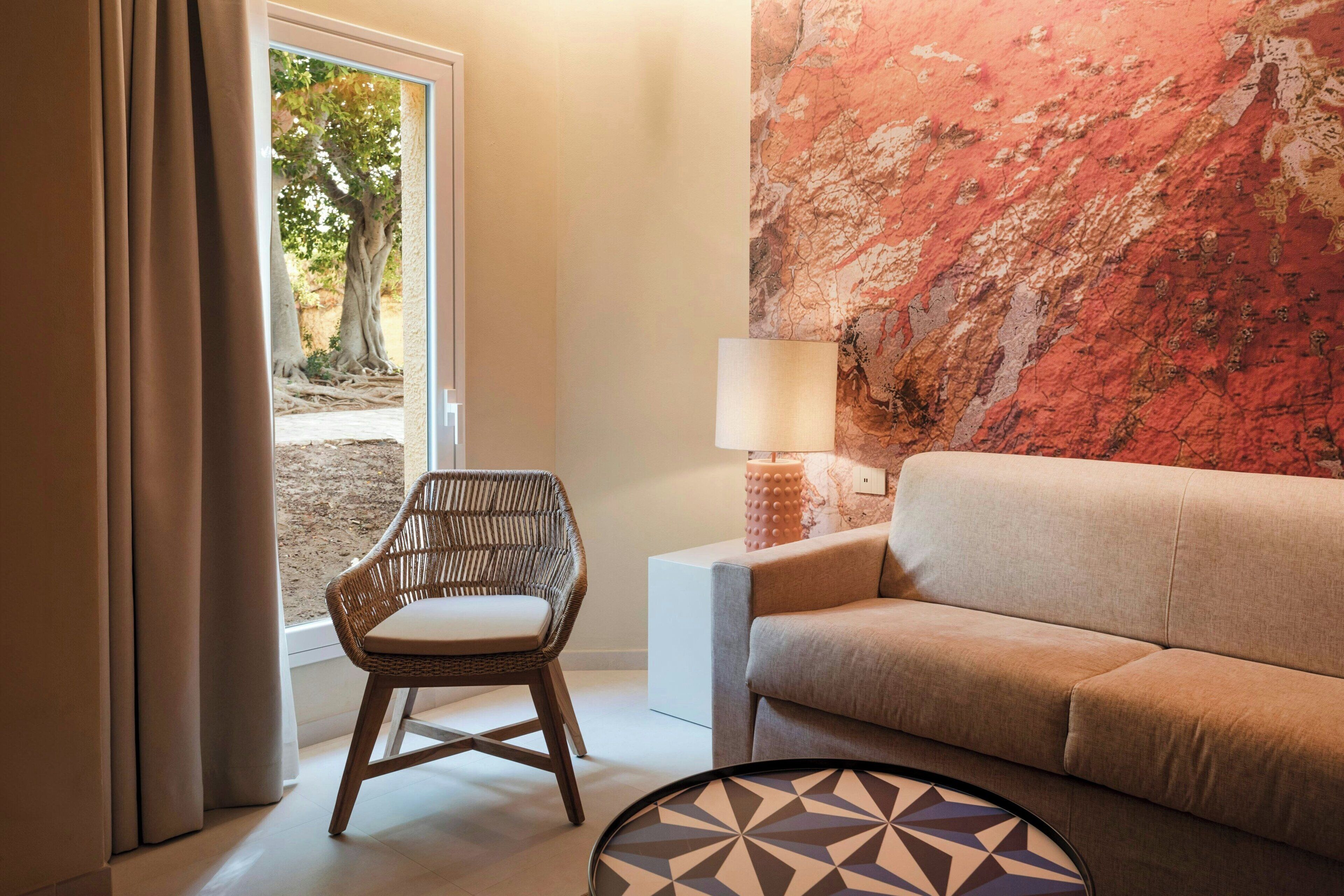 A modern living room with a wicker chair, a beige sofa, and a round coffee table.