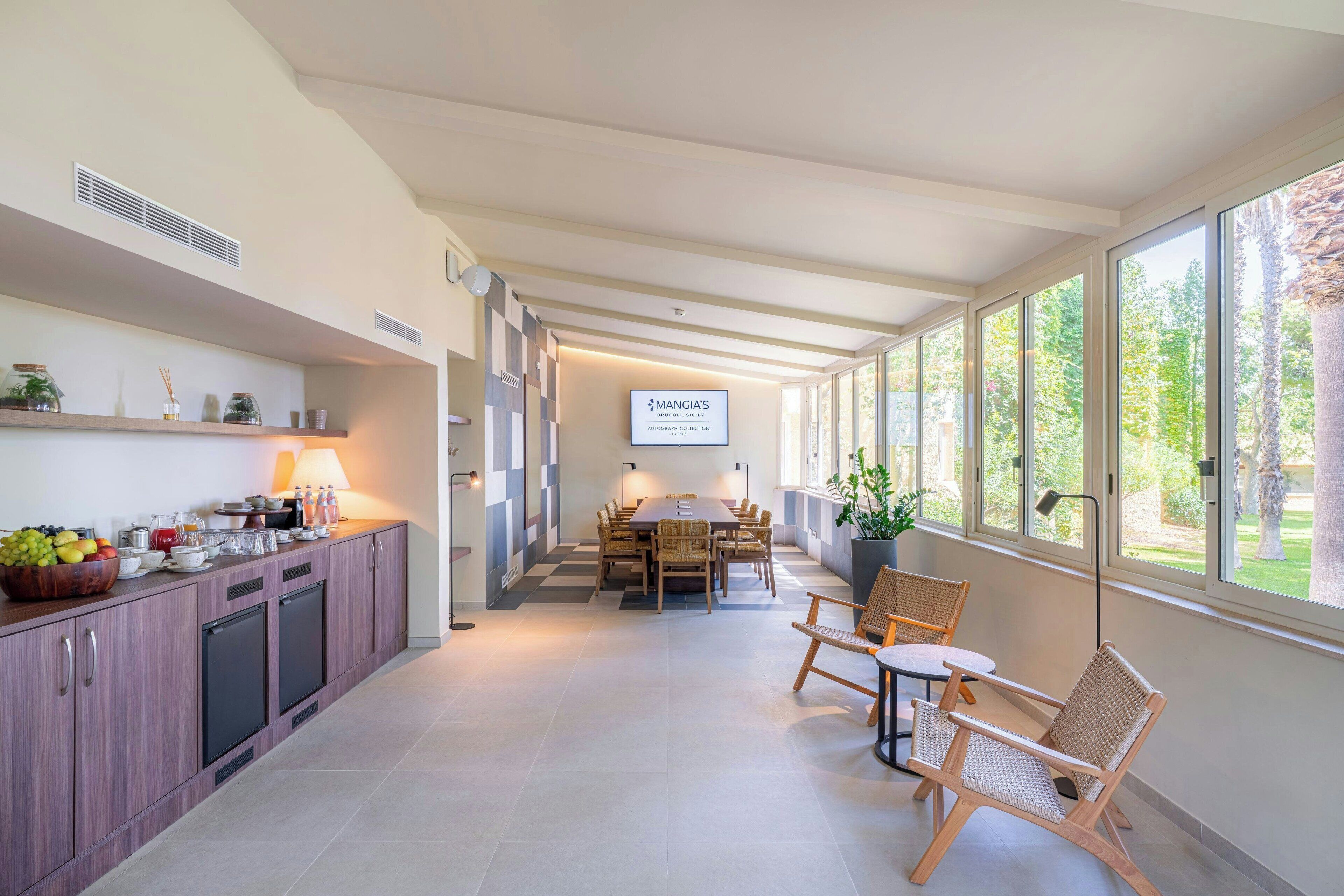 A modern hotel room with a dining area, kitchen, and large windows.