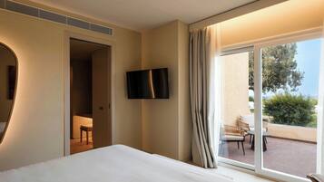 Une chambre d’hôtel dotée d’un grand lit, d’un téléviseur fixé au mur et d’un balcon avec des meubles d’extérieur.