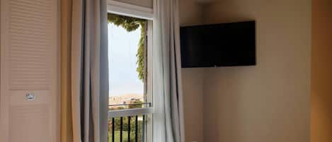 A hotel room with a bed, a TV mounted on the wall, and a window with curtains.