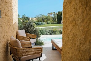 Relax in a serene outdoor setting with a pool, wicker chairs, and lush greenery.