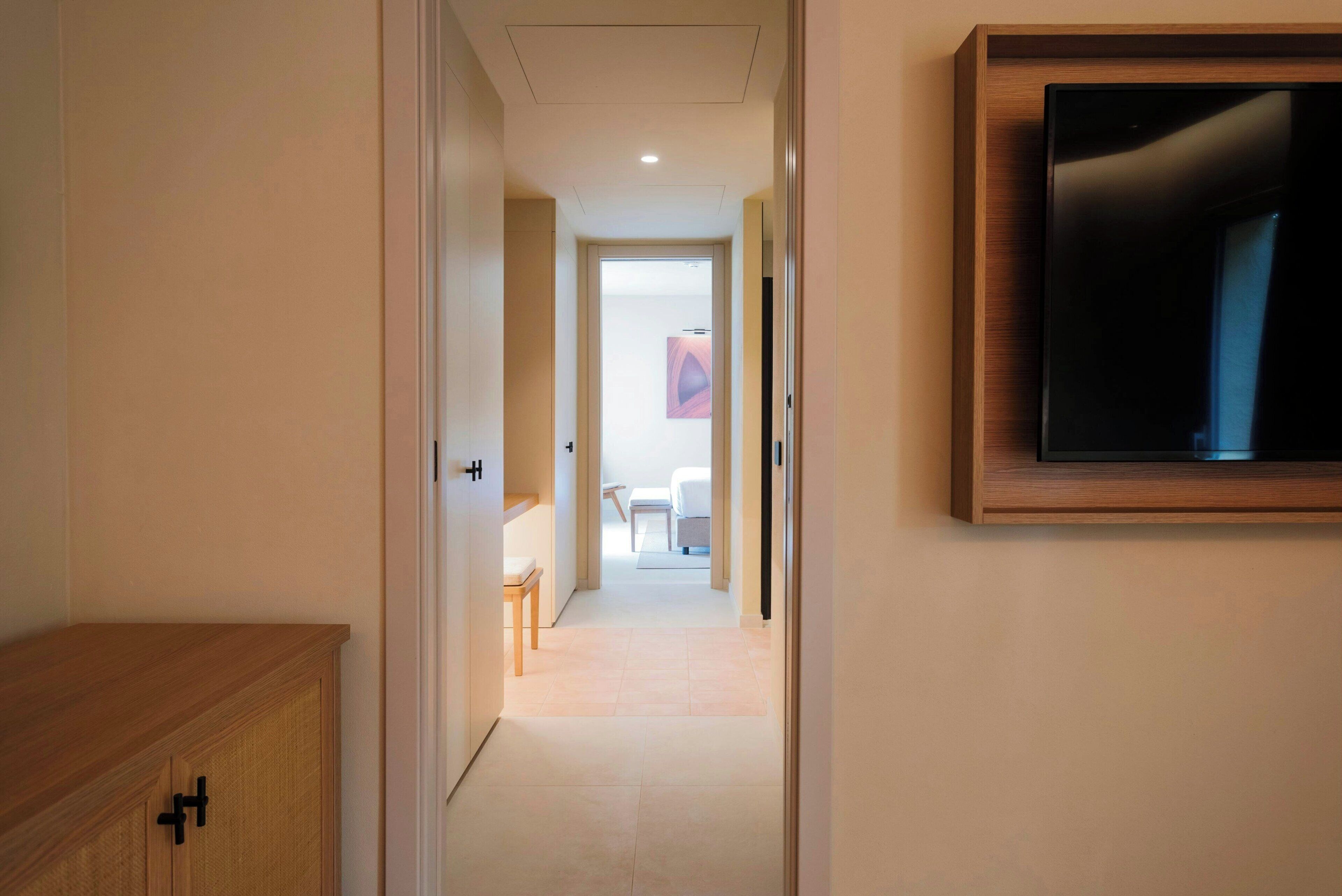 Un pasillo que conduce a un dormitorio con un televisor en la pared.