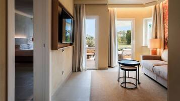 Une chambre d’hôtel moderne équipée d’un lit, d’un téléviseur fixé au mur, d’une petite table ronde, d’un canapé et offrant une vue sur l’extérieur grâce à une porte vitrée.