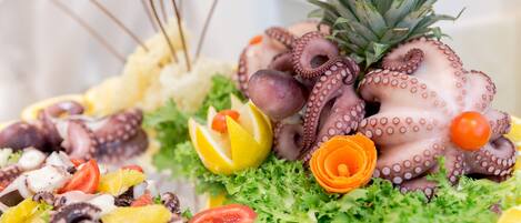 Een visplateau met oktopus tentakels, citroenpartjes, kerstomaatjes en een ananas.