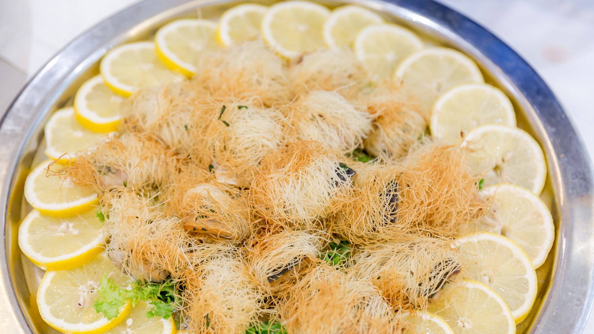 A tray of food with shredded toppings and lemon slices.