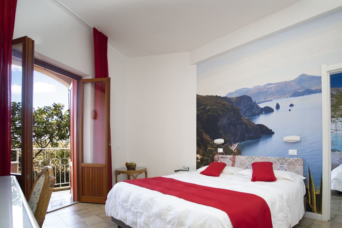 Un dormitorio con una cama grande, vistas al mar y un balcón.