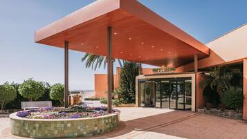 A modern building with a covered entrance, a tiled flower bed, and a bench.