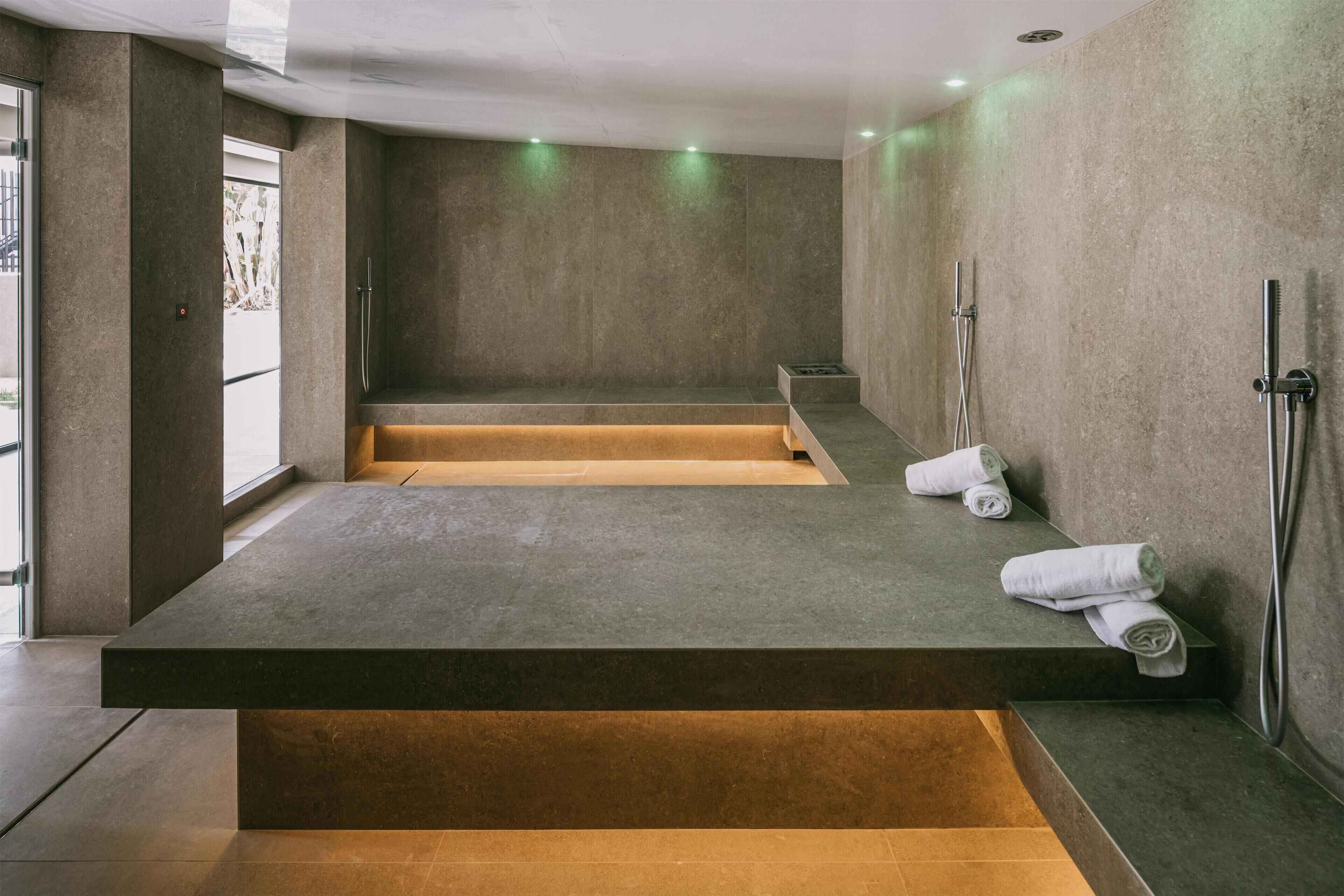 A modern bathroom with a large bathtub, a shower area, and a bench.