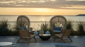 A terrace with wicker chairs and a round table, overlooking a body of water during sunset. - Mangia's Torre del Barone Resort and SPA (Sciacca)