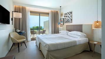 A hotel room with a bed, a TV, a desk, a chair, a table, and a balcony with a view.