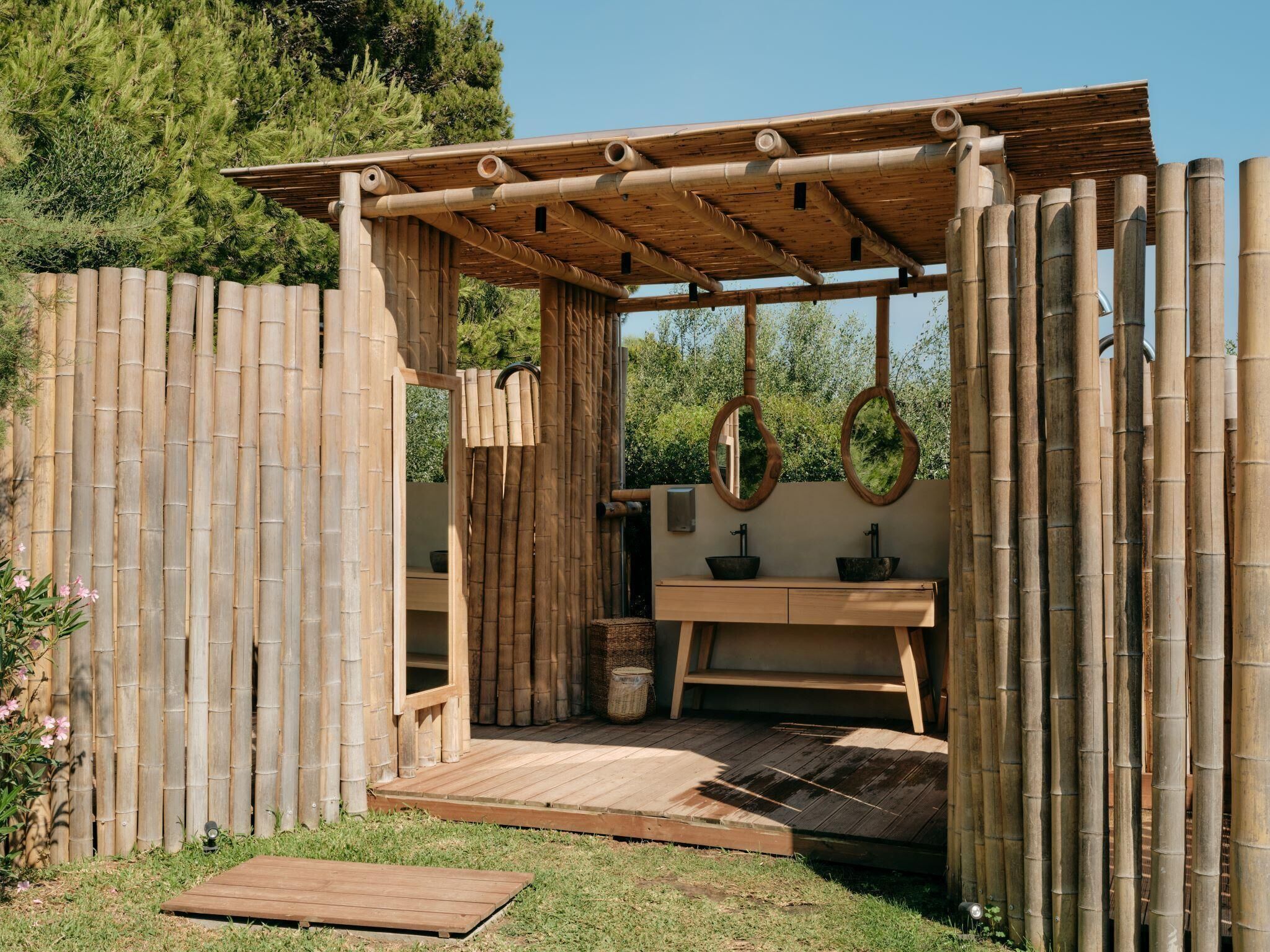 A bamboo structure with a wooden bench and a sink.