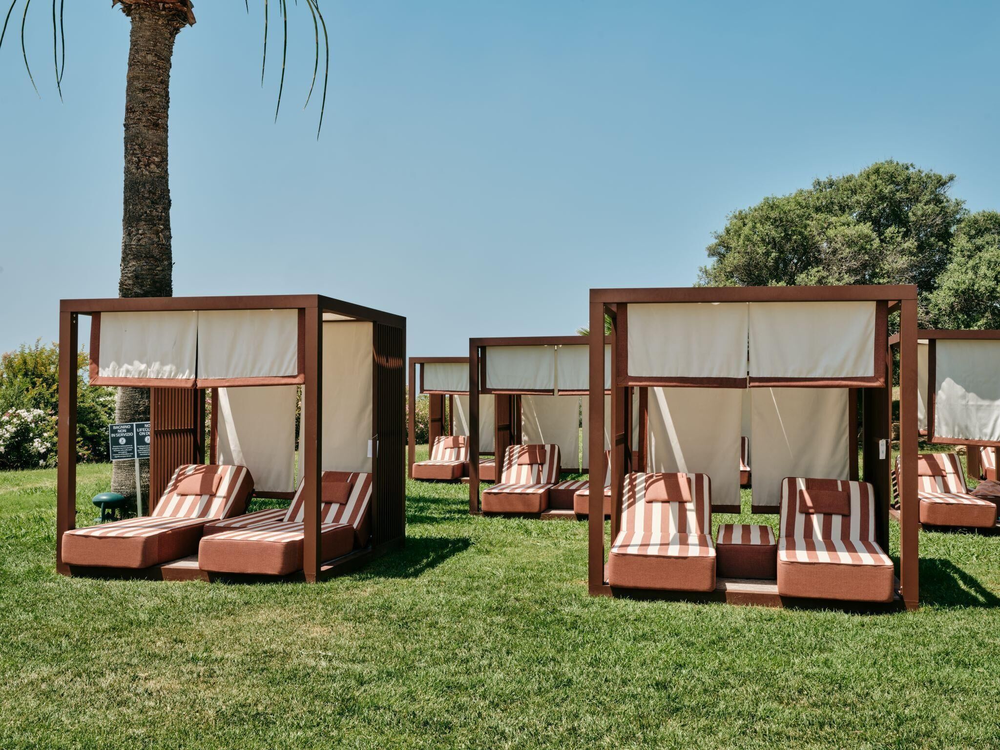 Des fauteuils de jardin, dotés de coussins à rayures, sont disposés en rangée sur une pelouse.