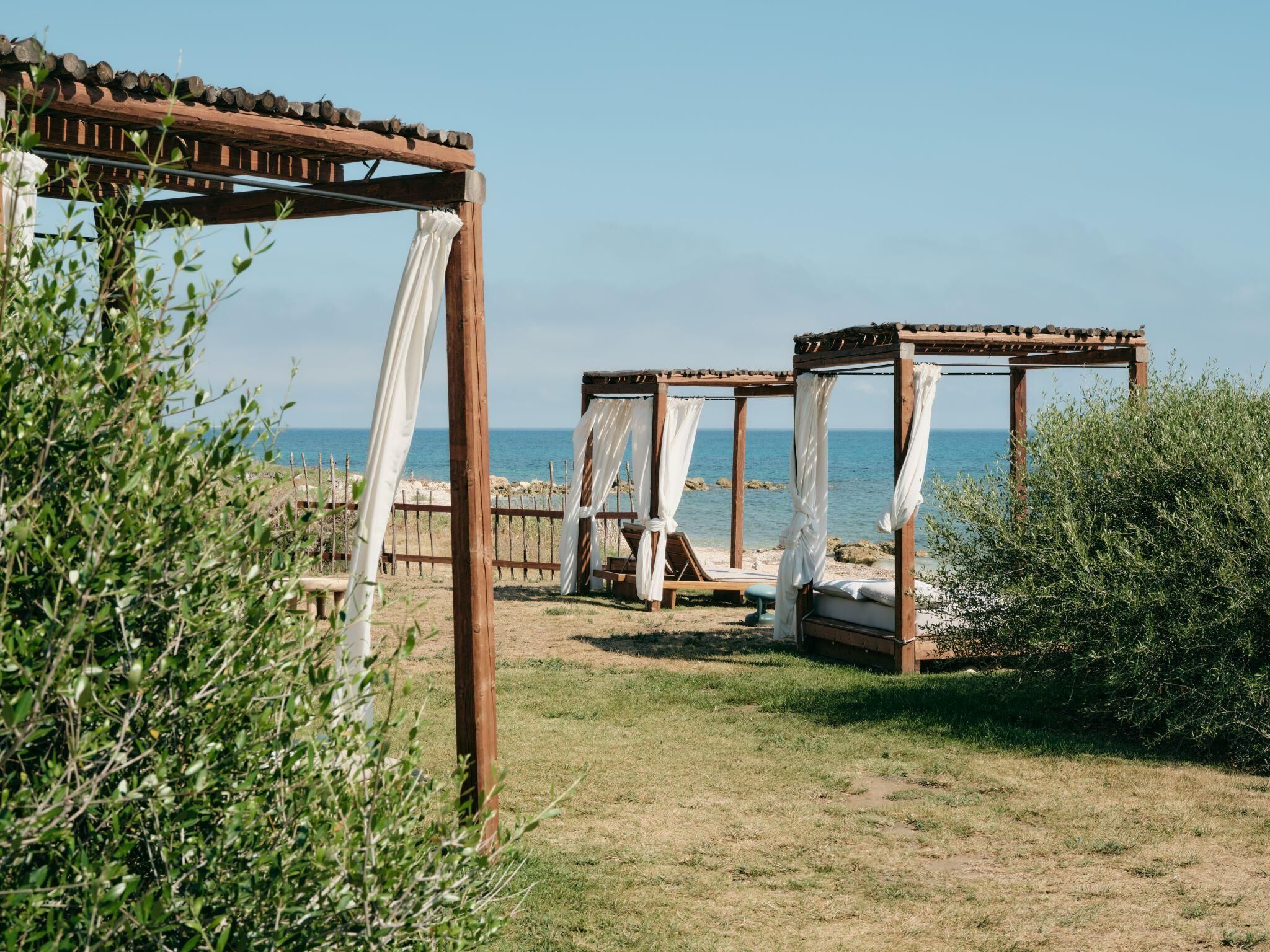 A beachside setting with wooden gazebos and a clear view of the sea.