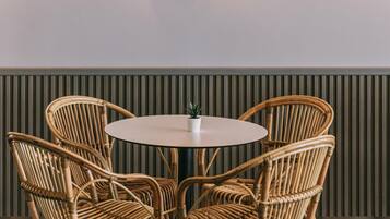 Een ronde tafel met zes rieten stoelen, een wandlamp en een paneel met strepen.