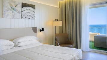 Une chambre d’hôtel avec un grand lit, une chaise, une lampe et une vue sur l’océan.
