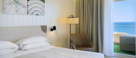 Une chambre d’hôtel avec un grand lit, une chaise, une lampe et une vue sur l’océan.
