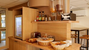 Ein Frühstücksbuffet mit Toaster, Brötchenkorb und Beilagen.