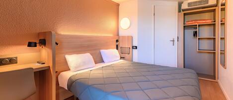 A bedroom with a bed, bedside table, lamp, and a wardrobe.
