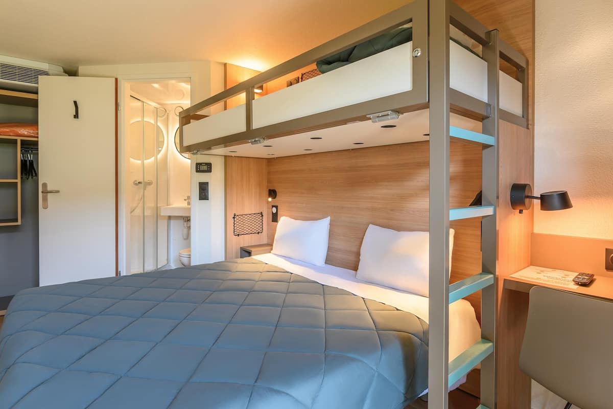 Habitación con literas, armario, ducha y mesita de noche.