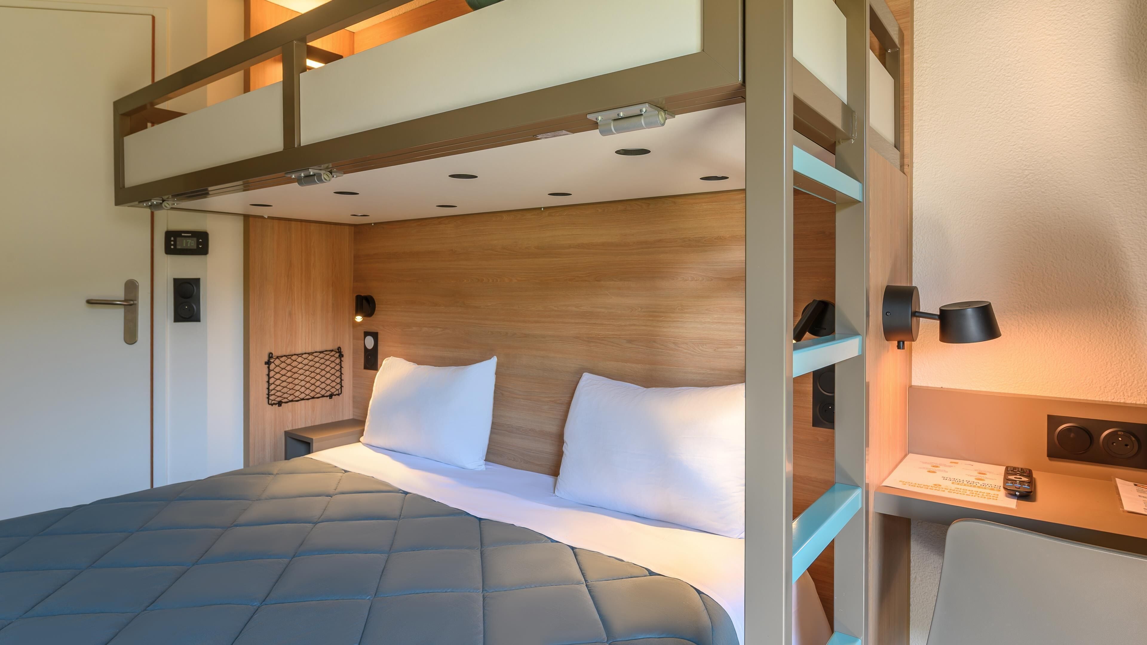 A bunk bed with a headboard, a bedside table with a lamp, and a wall-mounted clock.
