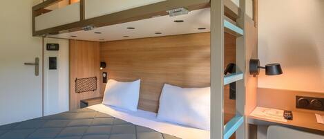 A bunk bed with a headboard, a bedside table with a lamp, and a wall-mounted clock.