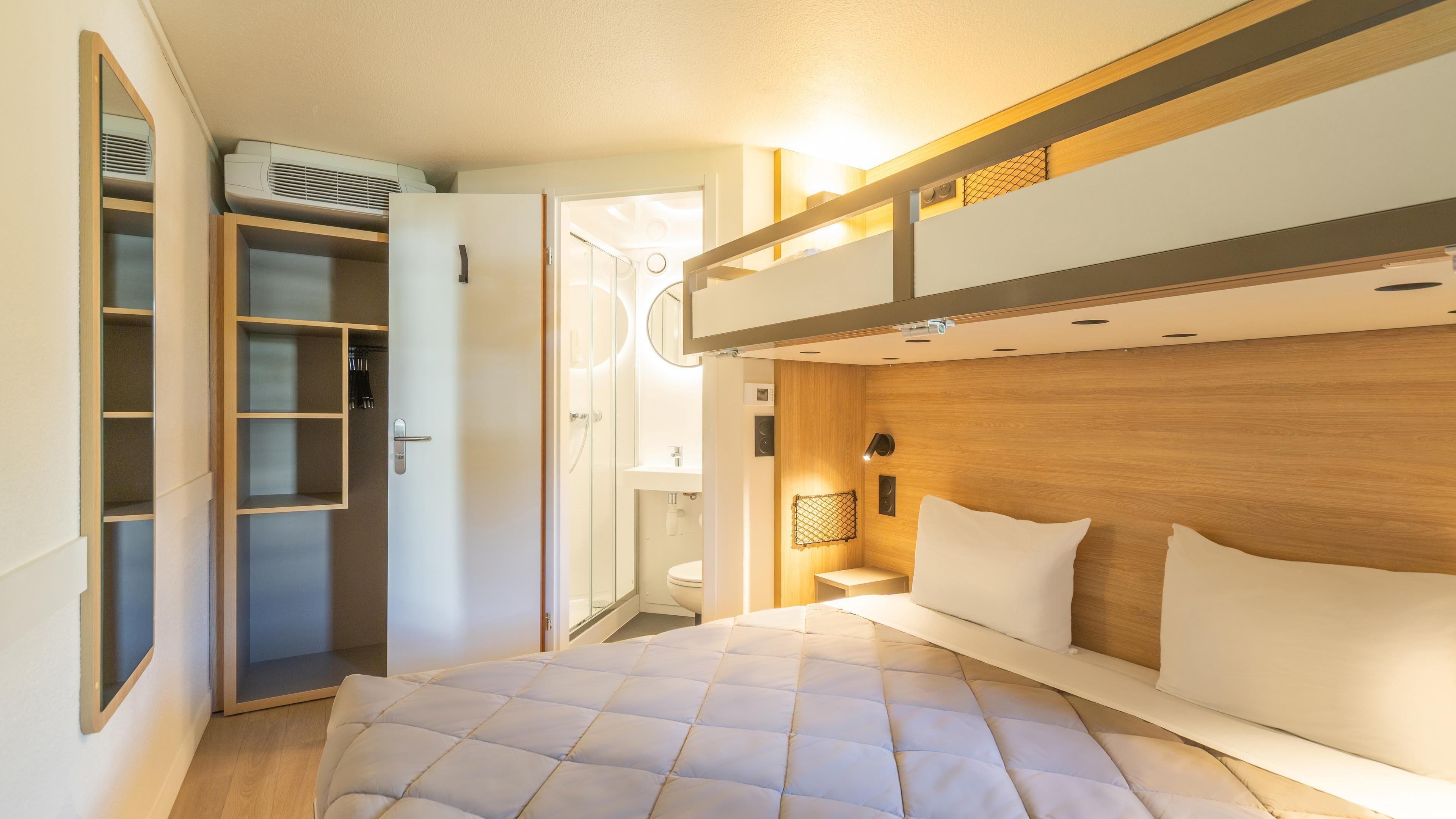A compact bedroom with a bunk bed, a walk-in closet, and a bathroom with a toilet and sink.