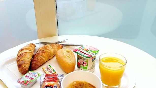 A breakfast tray with croissants, bread, yogurt, juice, and coffee on a white plate. - Premiere Classe Saint Brice Sous Forêt (Saint-Brice-sous-Foret)