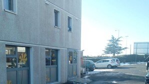 A multi-story building with large windows and a parking area. - Premiere Classe Saint Brice Sous Forêt (Saint-Brice-sous-Foret)