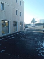 Um edifício com vários andares, janelas amplas e estacionamento.