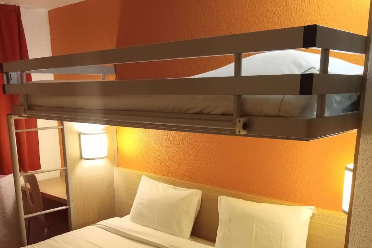 A bunk bed with a wooden frame, white bedding, and two bedside lamps.