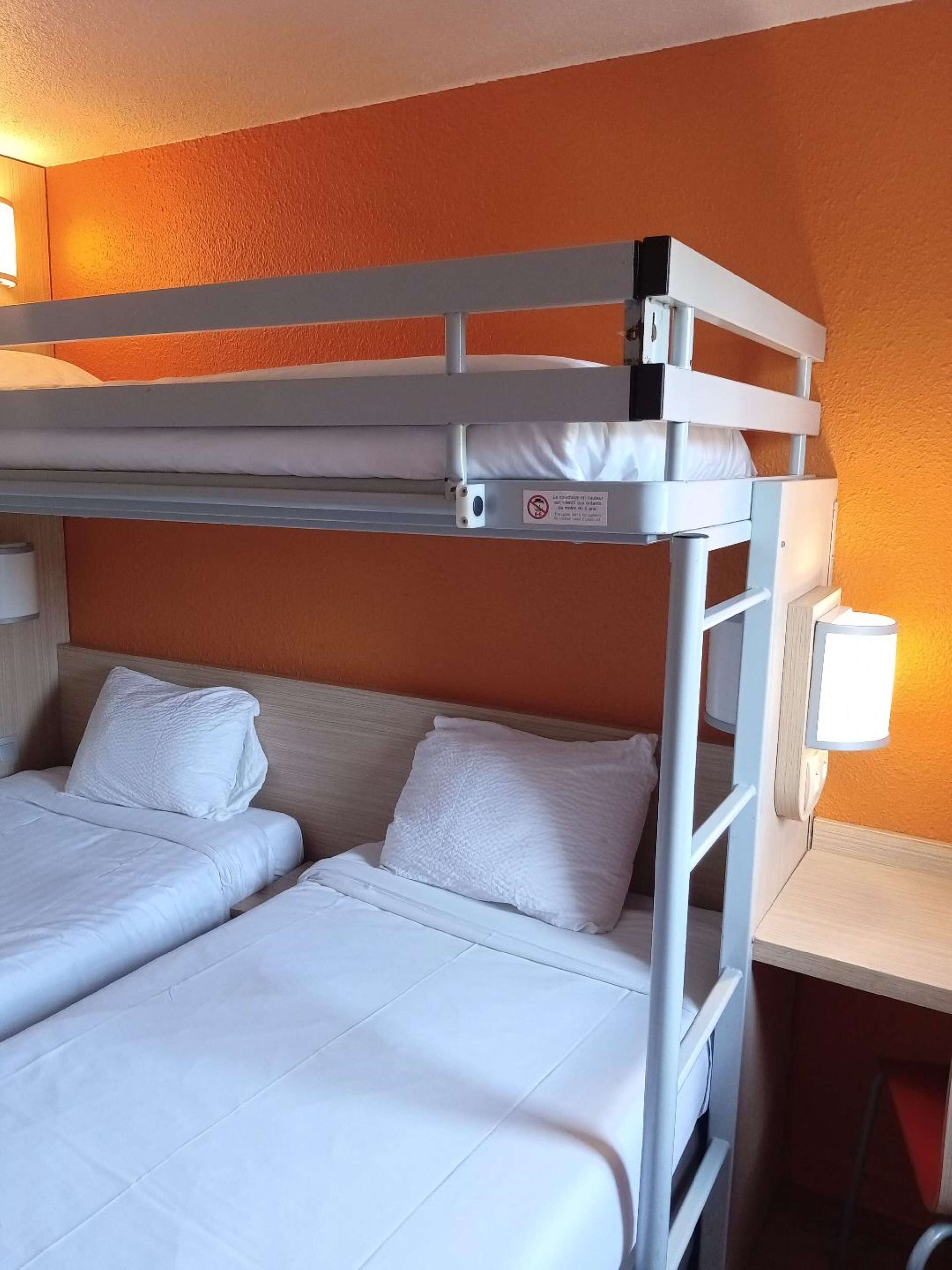 Habitación con literas, un escritorio y una lámpara.