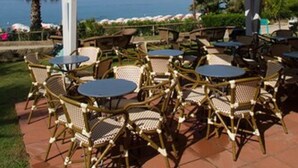 An outdoor patio with wicker furniture and a view of the sea. - MClub Lipari (Sciacca)