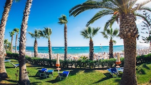 A beach resort with palm trees, sun loungers, and umbrellas.