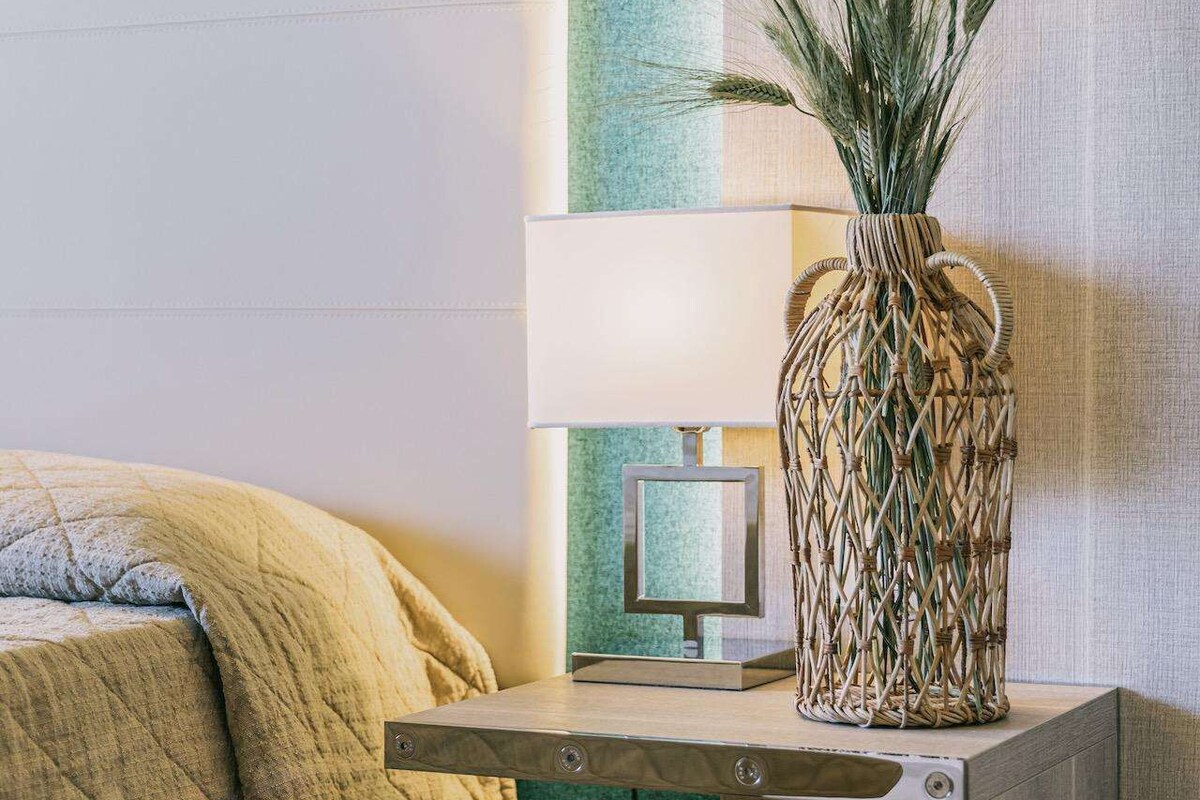 A bedroom with a bed, bedside table, lamp, and a small monitor.