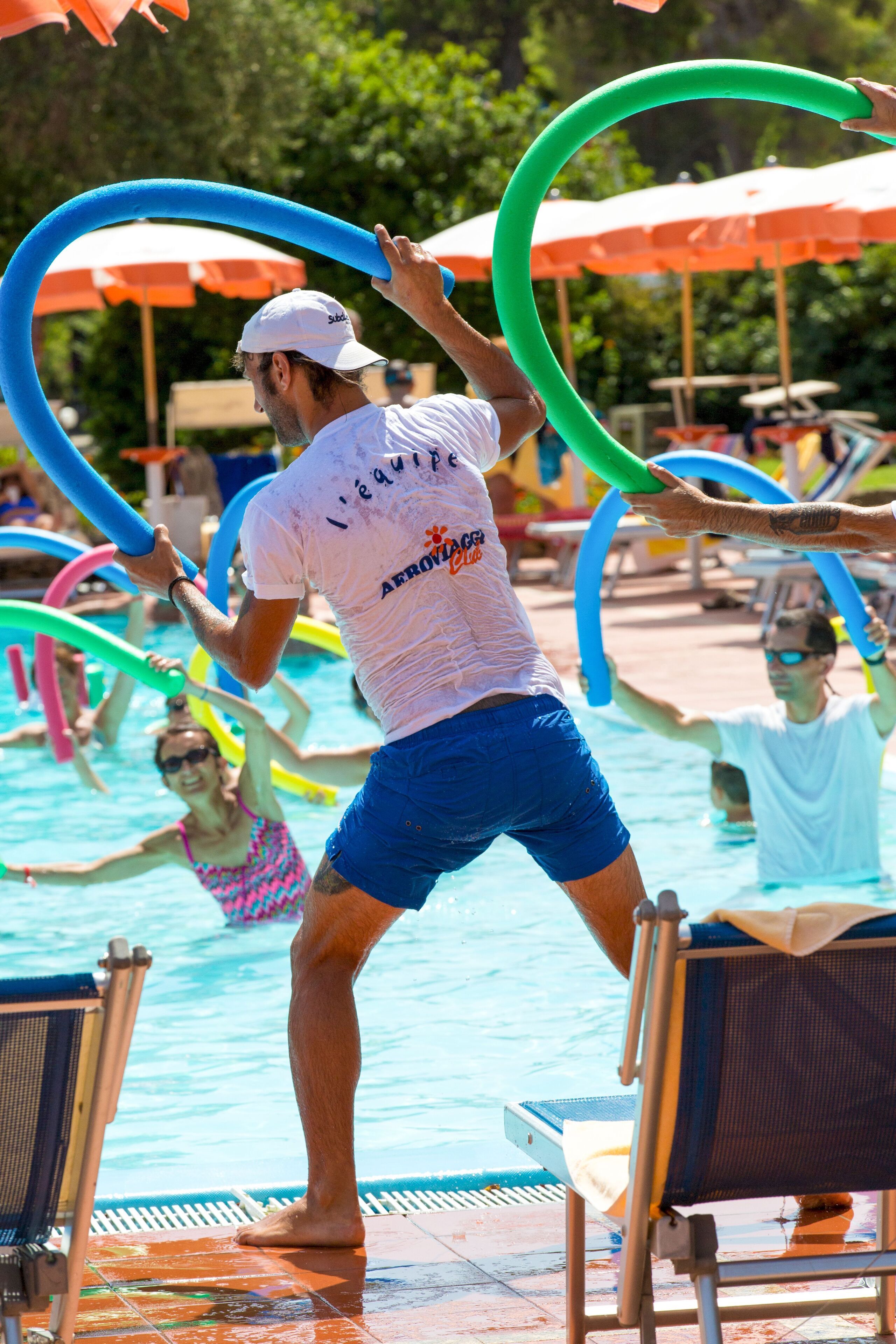 A pool area with people playing with inflatable rings.