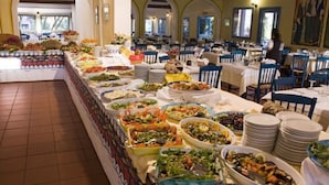 A buffet setup with various food items and a dining area with tables and chairs. - Agrustos Village (Budoni)